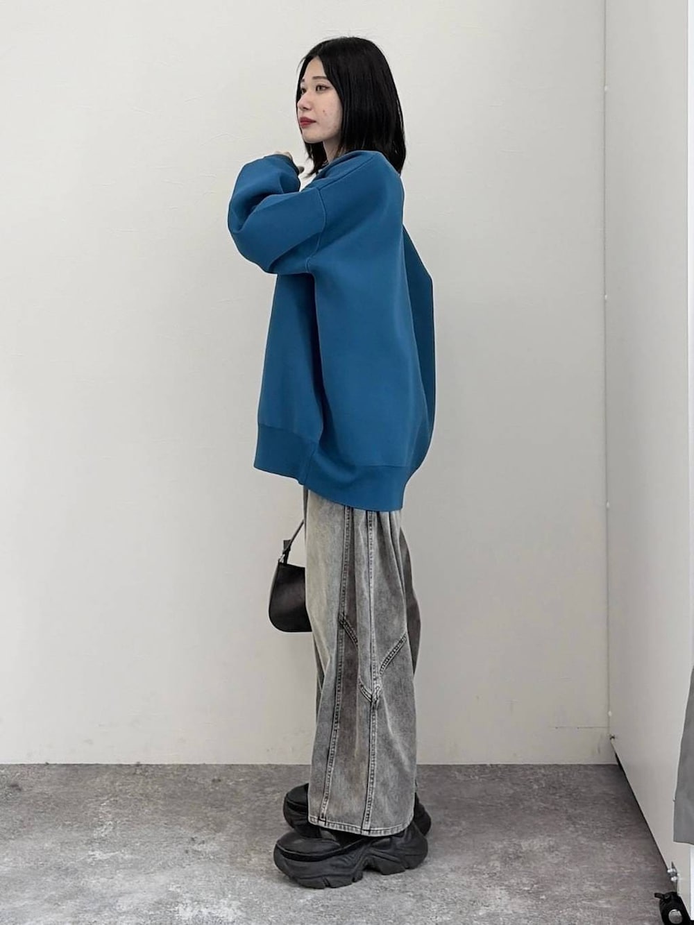 ブラック系のブーツ、ブラック系のハンドバッグ、ブルー系のカーディガン/ボレロを着用したレディースの冬コーディネートの2枚目の写真