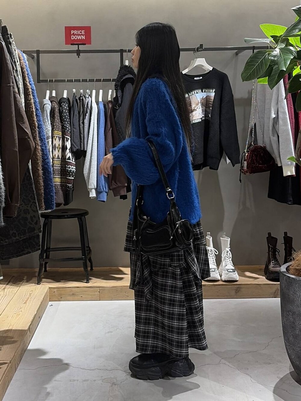 ブラック系のブーツ、ホワイト系のスカート、グレー系のニット/セーターを着用したレディースの冬コーディネートの2枚目の写真