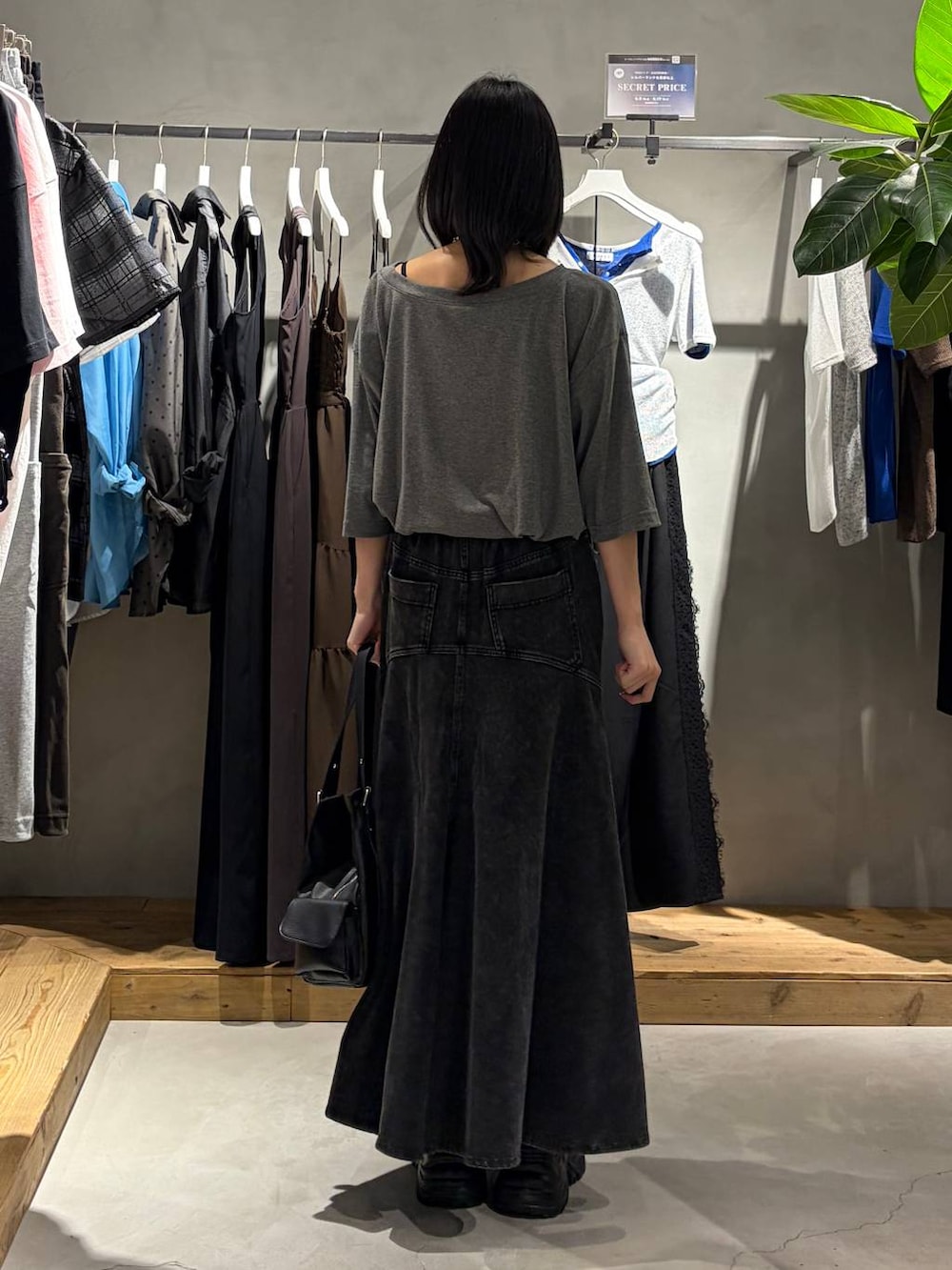 ブラック系のスニーカー、ブラック系のデニムスカート、ブラック系のハンドバッグを着用したレディースの夏コーディネートの3枚目の写真