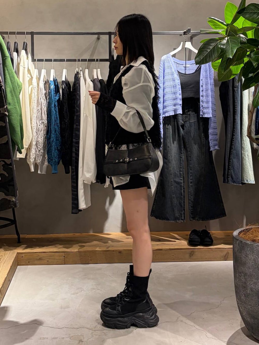 ブラック系のブーツ、ブラック系のハンドバッグ、ブラック系のベストを着用したレディースの春コーディネートの2枚目の写真