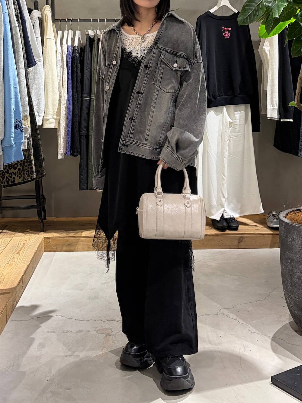 ブラック系のブーツ、ブラック系のデニムパンツ、ホワイト系のボストンバッグを着用したレディースの冬コーディネートの6枚目の写真