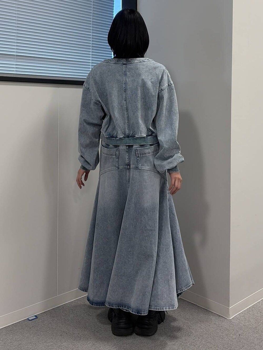 ブラック系のブーツ、ブラック系のニット/セーター、ブルー系のデニムスカートを着用したレディースの冬コーディネートの3枚目の写真