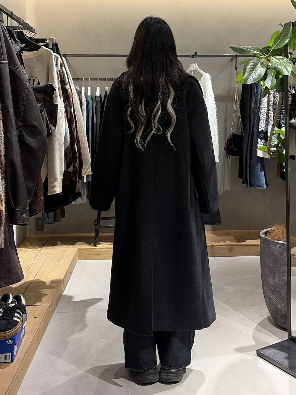 ブラック系のブーツ、ブルー系のデニムパンツ、ブラック系のチェスターコートを着用したレディースの冬コーディネートの3枚目の写真