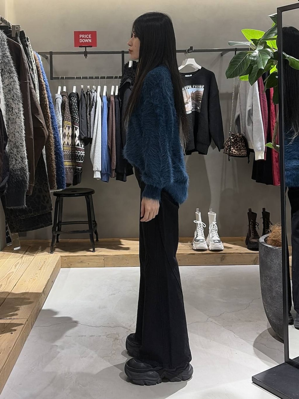 ブラック系のブーツ、ブラック系のデニムパンツ、ブルー系のニット/セーターを着用したレディースの冬コーディネートの2枚目の写真