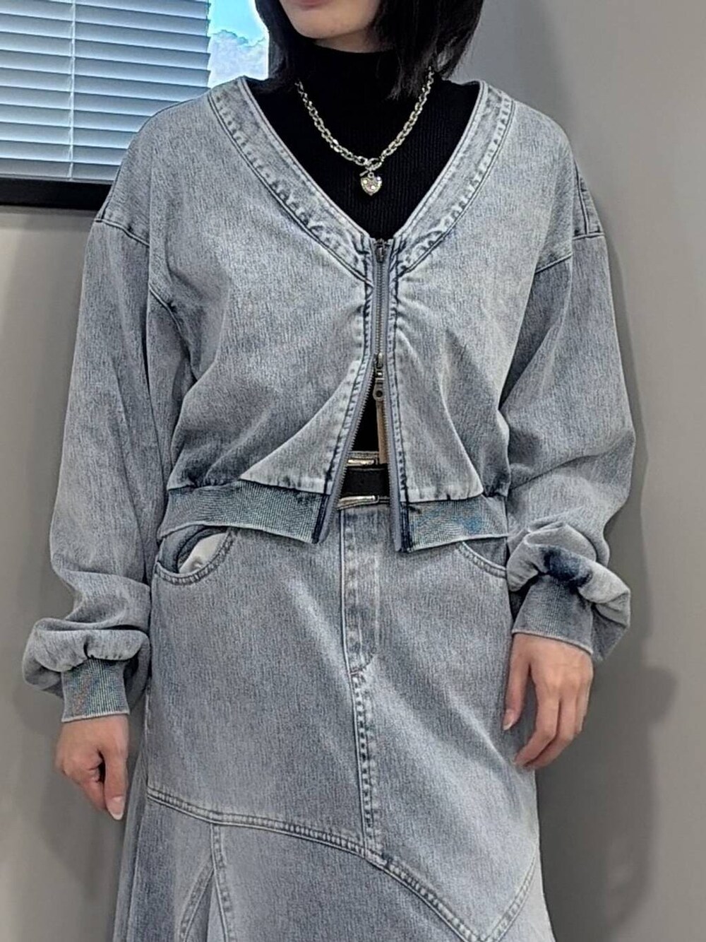 ブラック系のブーツ、ブラック系のニット/セーター、ブルー系のデニムスカートを着用したレディースの冬コーディネートの4枚目の写真