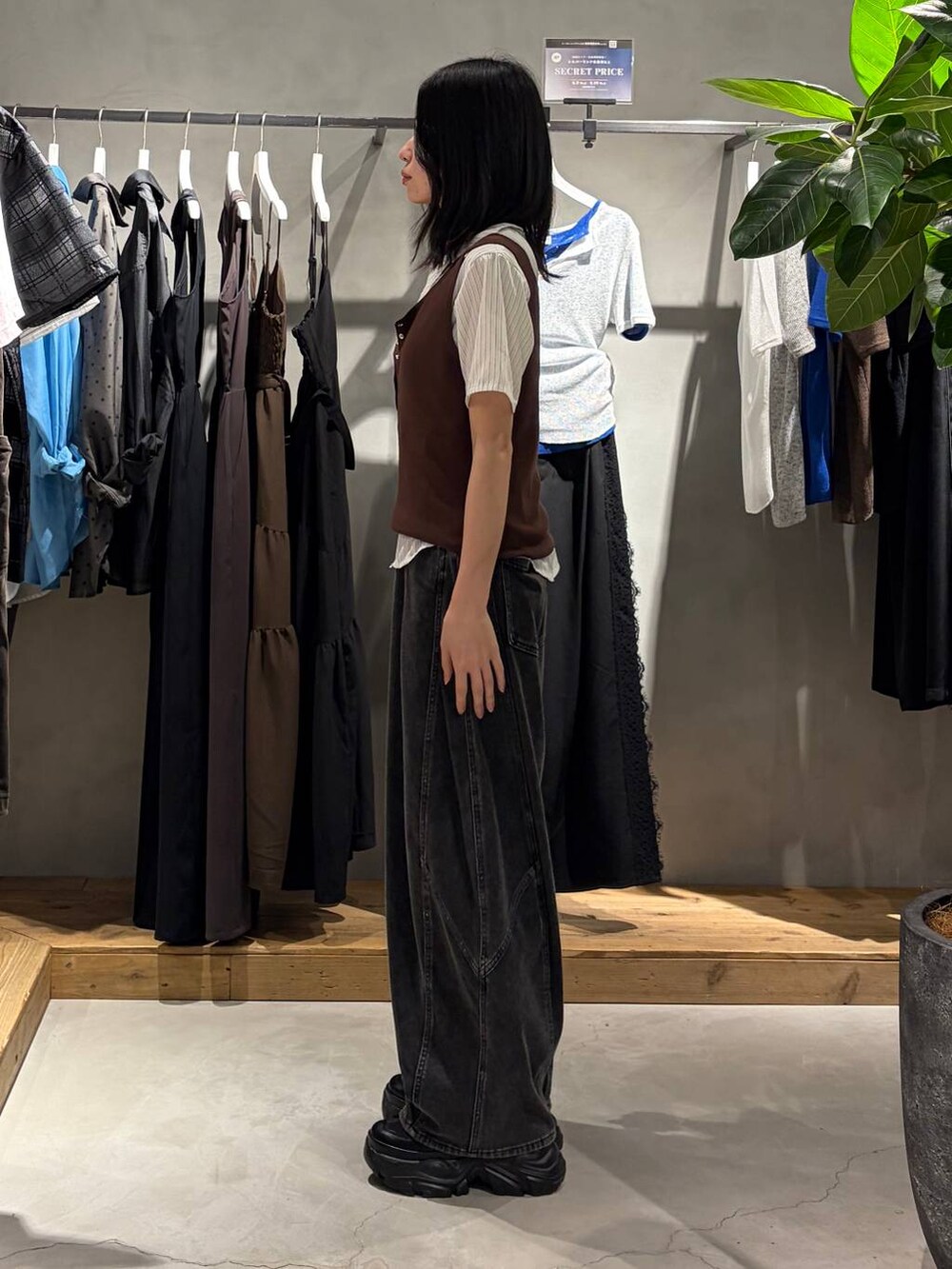 ブラック系のスニーカー、ブラック系のデニムパンツ、ブラウン系のタンクトップを着用したレディースの夏コーディネートの2枚目の写真