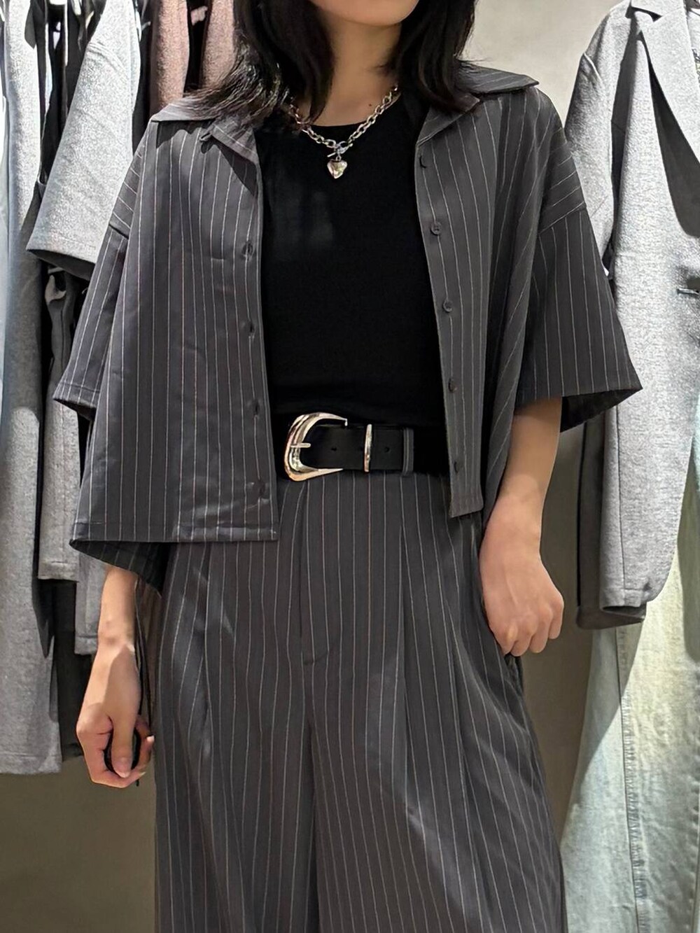 ブラック系のサンダル、ブラック系のTシャツ/カットソー、グレー系のスラックスを着用したレディースの夏コーディネートの4枚目の写真