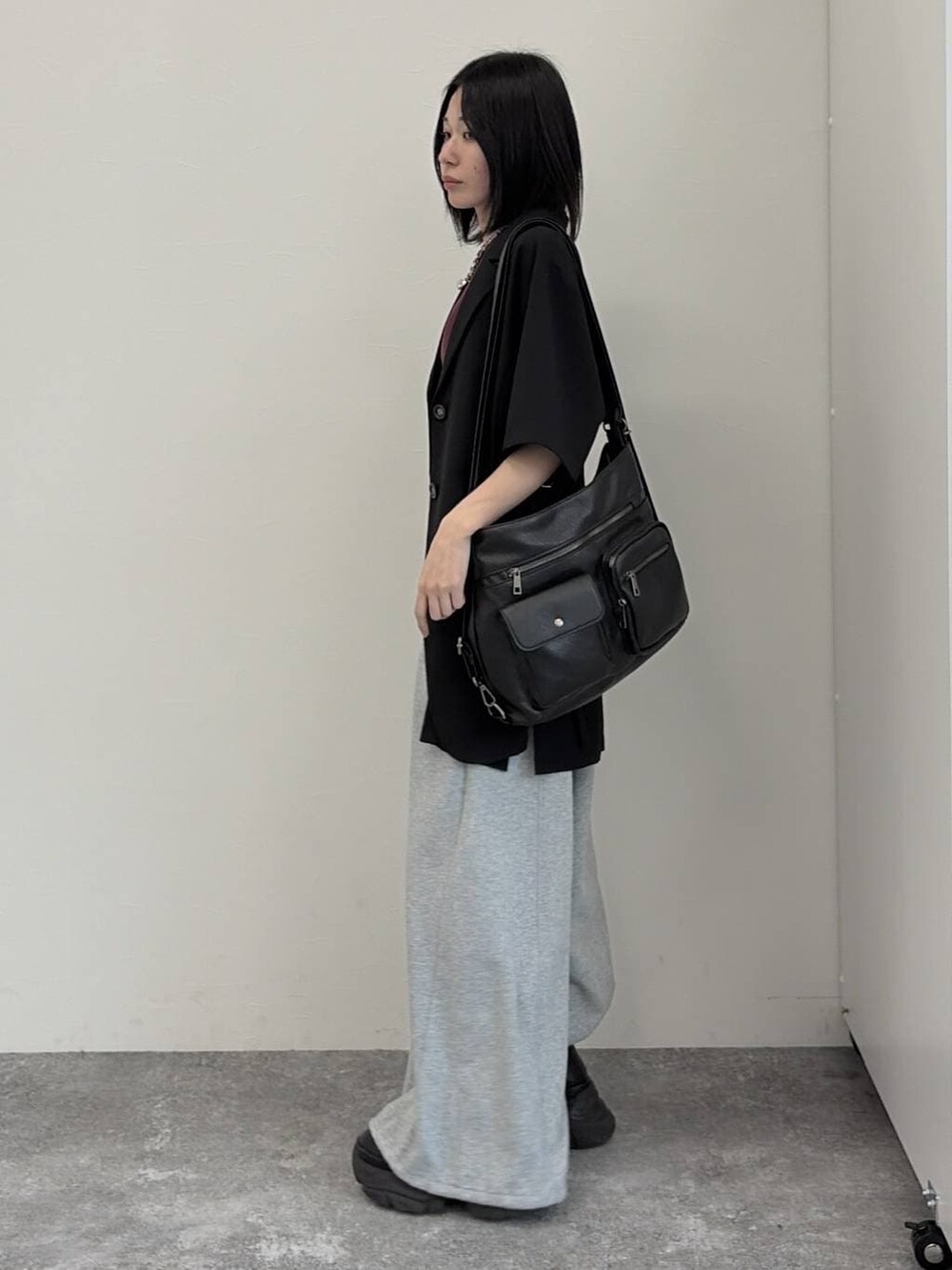 グレー系のスウェットパンツ、ブラック系のショルダーバッグ、ブラック系のテーラードジャケットを着用したレディースの春コーディネートの2枚目の写真