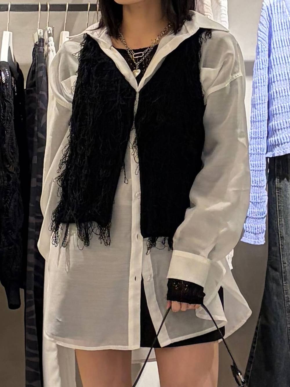 ブラック系のブーツ、ブラック系のハンドバッグ、ブラック系のベストを着用したレディースの春コーディネートの4枚目の写真