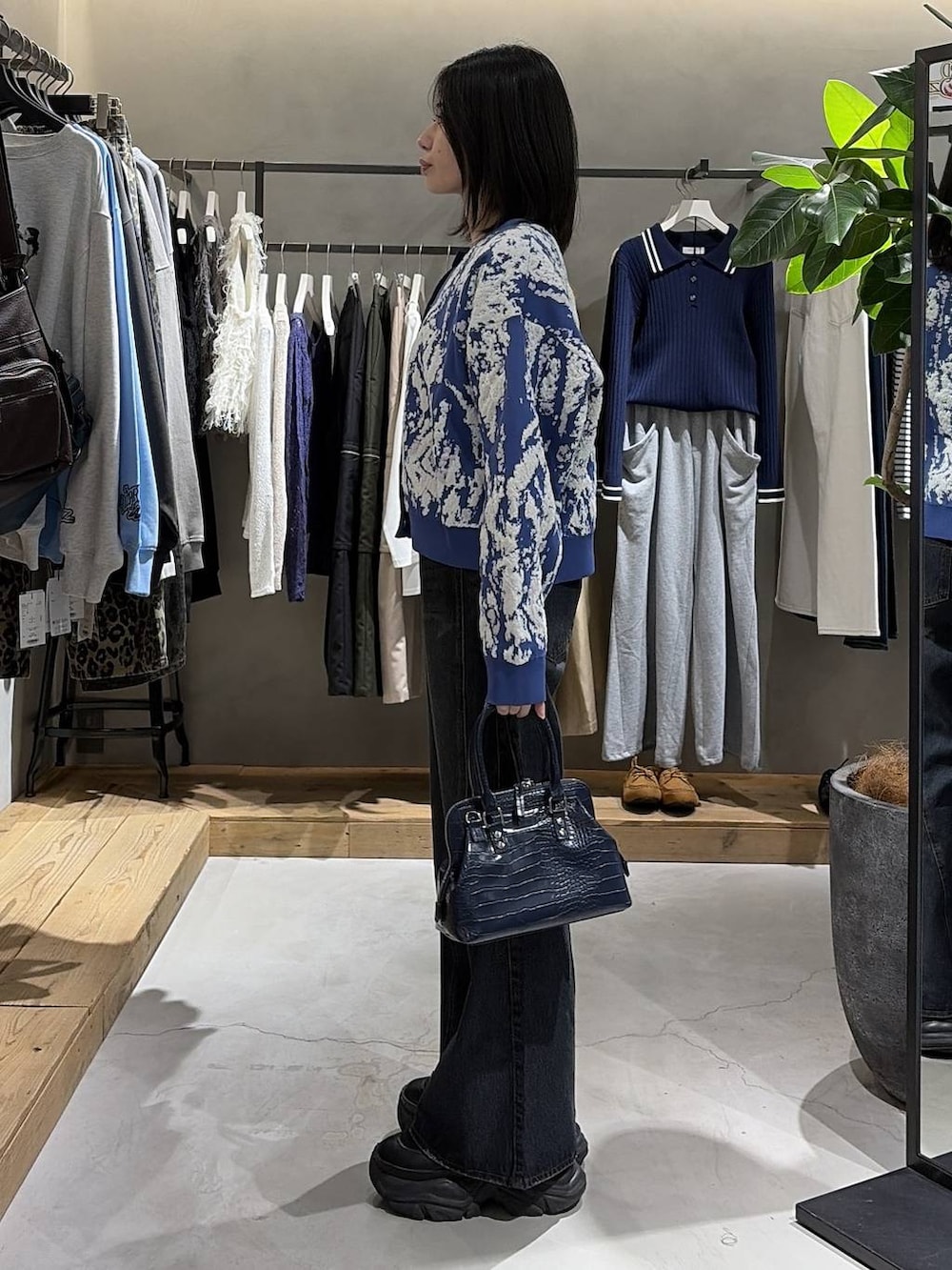 ブラック系のブーツ、ブルー系のデニムパンツ、ブルー系のハンドバッグを着用したレディースの冬コーディネートの2枚目の写真