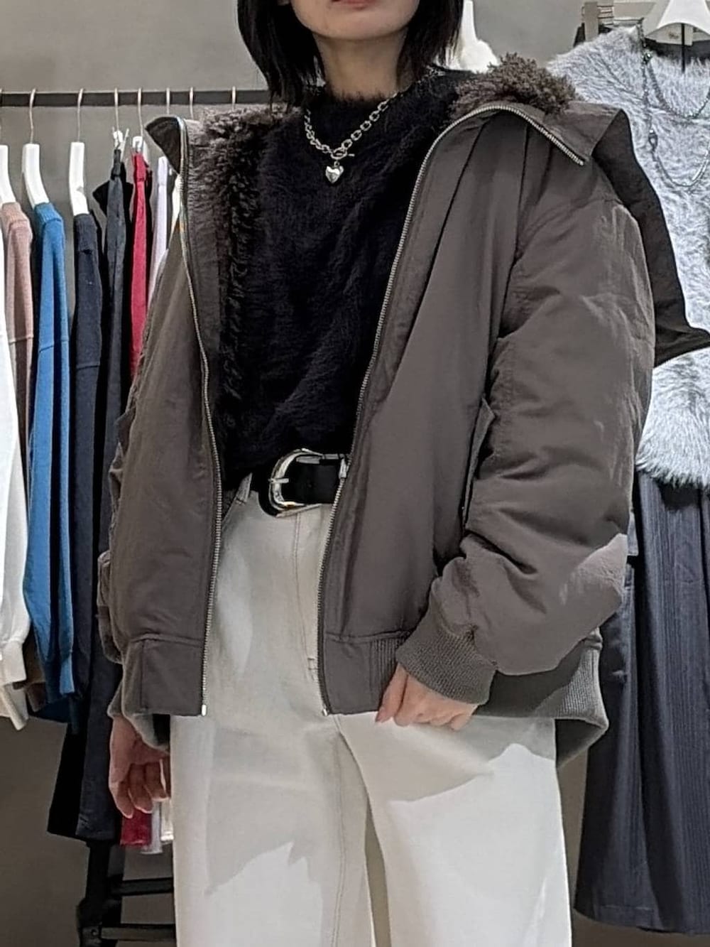 ブラウン系のブルゾン、ブラック系のニット/セーター、ホワイト系のスラックスを着用したレディースの冬コーディネートの4枚目の写真