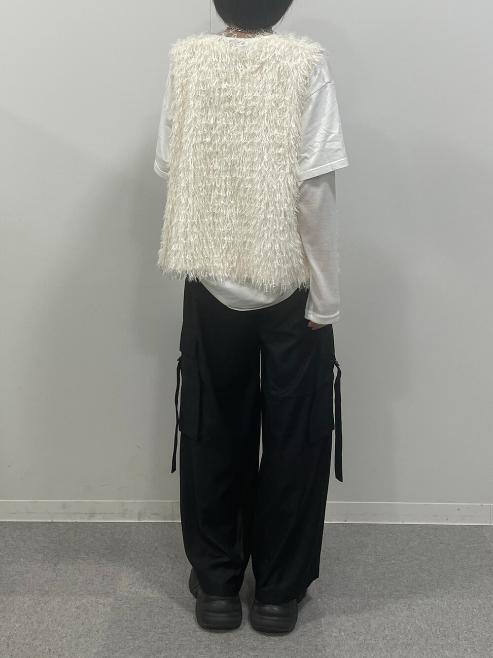 ホワイト系のTシャツ/カットソー、ホワイト系のベスト、ブラック系のブーツを着用したレディースの秋コーディネートの3枚目の写真