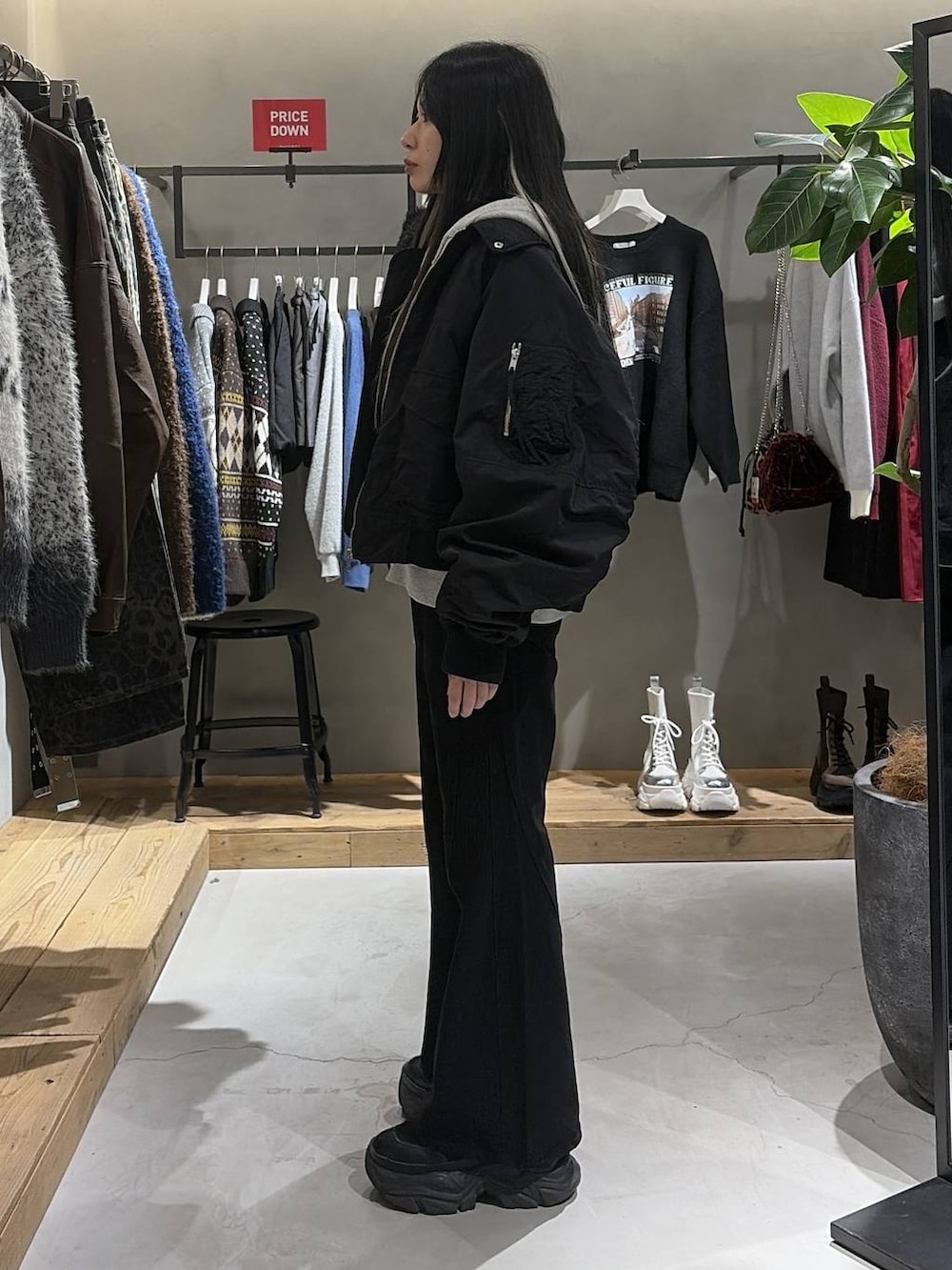 ブラック系のブーツ、ブラック系のデニムパンツ、グレー系のパーカーを着用したレディースの冬コーディネートの2枚目の写真