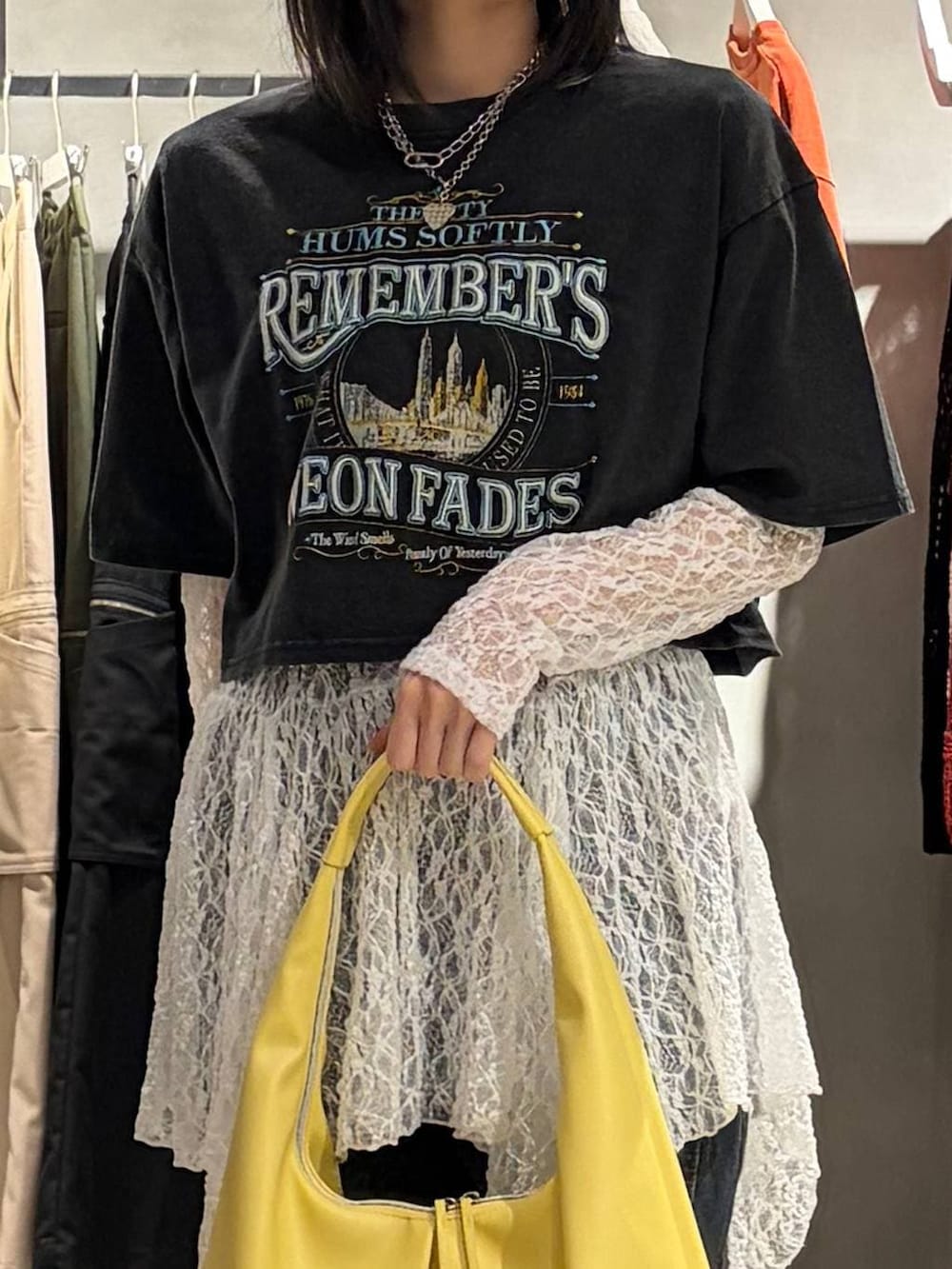 ブルー系のデニムパンツ、イエロー系のトートバッグ、ホワイト系のチュニックを着用したレディースの春コーディネートの4枚目の写真