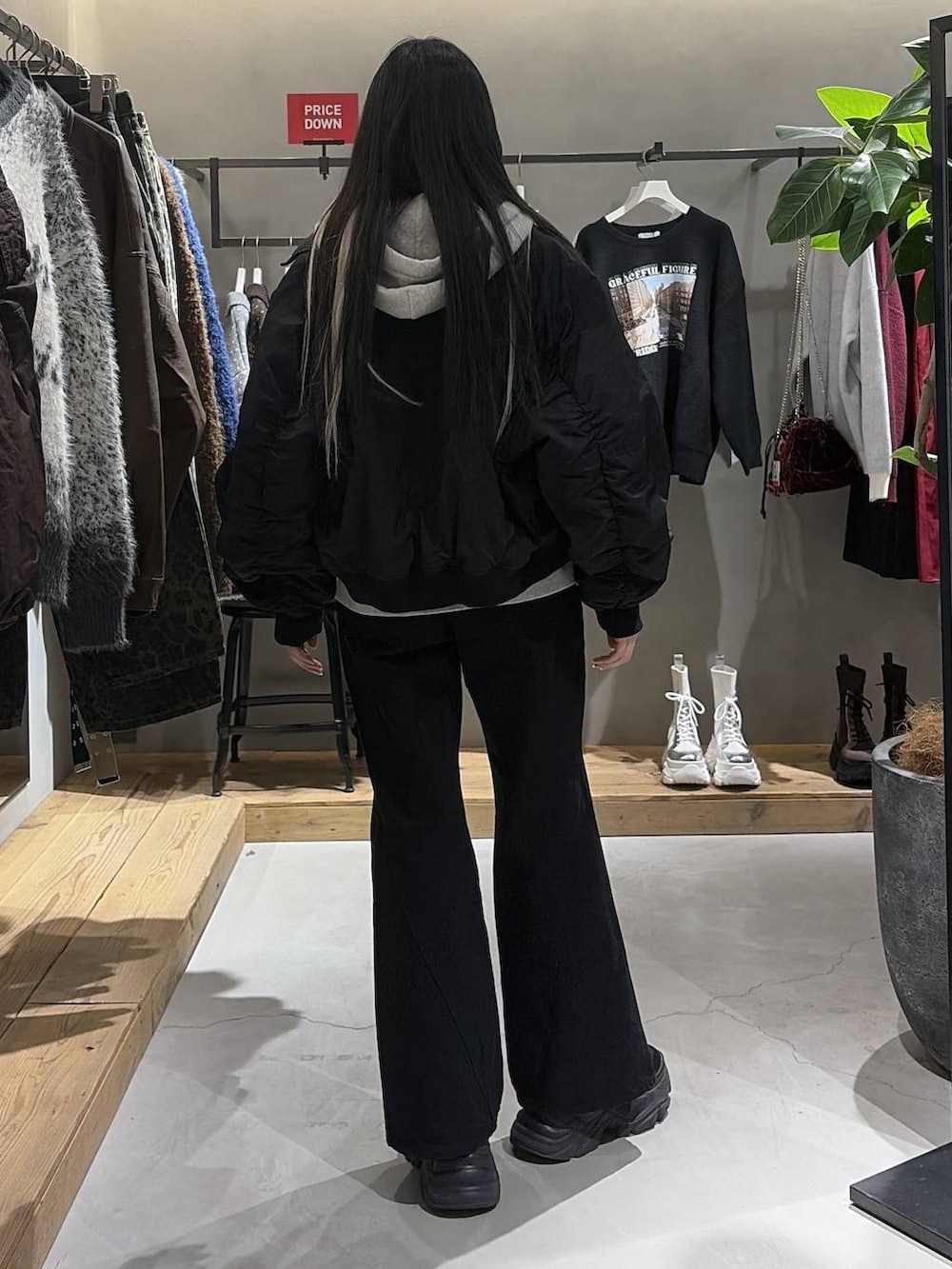 ブラック系のブーツ、ブラック系のデニムパンツ、グレー系のパーカーを着用したレディースの冬コーディネートの3枚目の写真