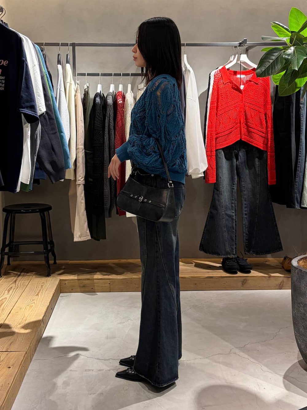 ブルー系のカーディガン/ボレロ、ブルー系のデニムパンツ、ブラック系のハンドバッグを着用したレディースの春コーディネートの2枚目の写真