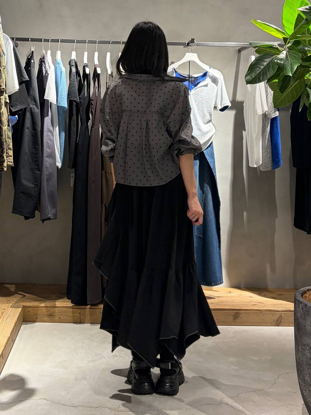 ブラック系のスカート、ブラック系のサンダル、ホワイト系のタンクトップを着用したレディースの夏コーディネートの3枚目の写真