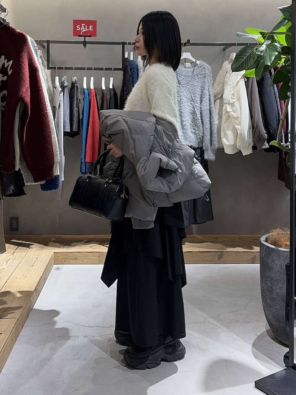 グレー系のブルゾン、ブラック系のスカート、ブラック系のボストンバッグを着用したレディースの冬コーディネートの2枚目の写真