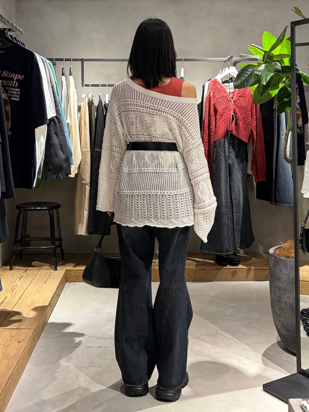 ブラック系のブーツ、ブルー系のデニムパンツ、ブラック系のハンドバッグを着用したレディースの春コーディネートの3枚目の写真