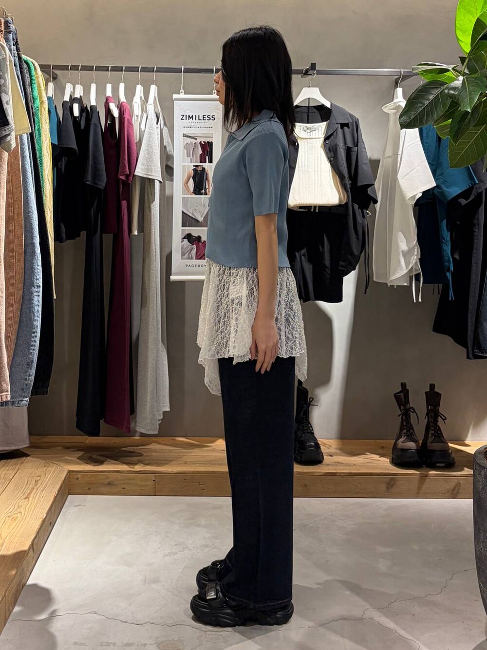 ブルー系のデニムパンツ、ブラック系のサンダル、ホワイト系のチュニックを着用したレディースの春コーディネートの2枚目の写真