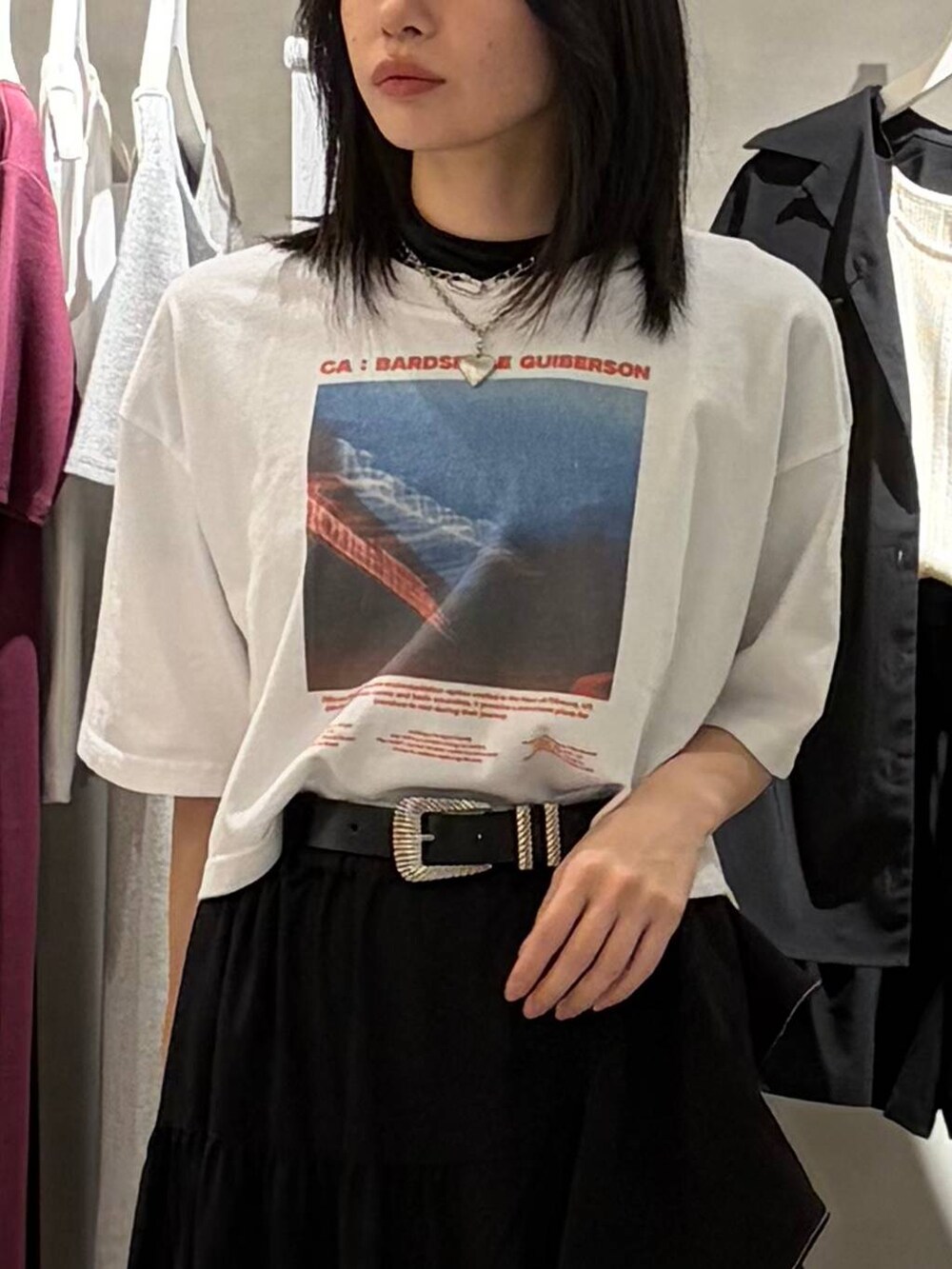 ブラック系のスカート、ブラック系のサンダル、ホワイト系のTシャツ/カットソーを着用したレディースの春コーディネートの4枚目の写真