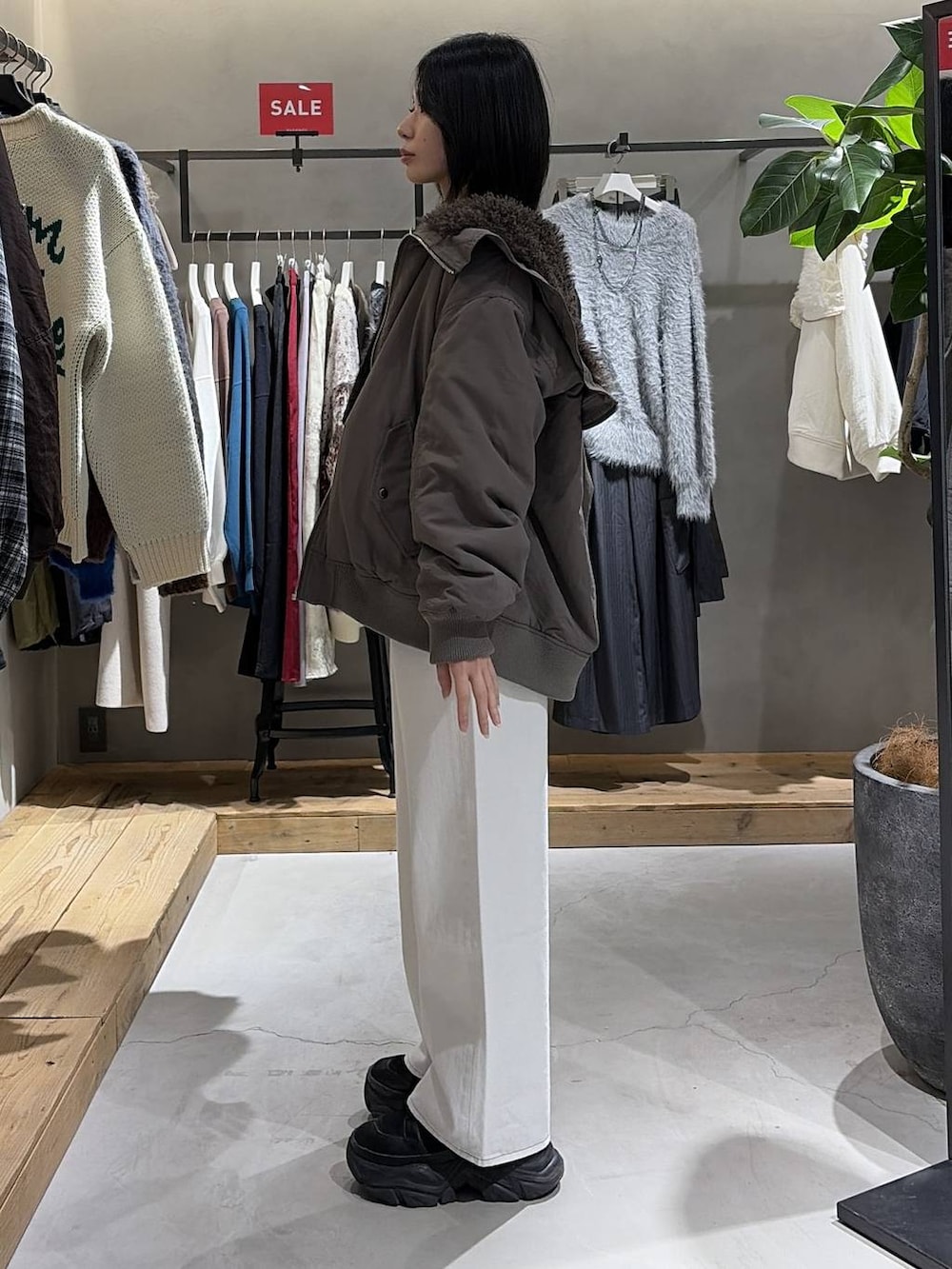 ブラウン系のブルゾン、ブラック系のニット/セーター、ホワイト系のスラックスを着用したレディースの冬コーディネートの2枚目の写真