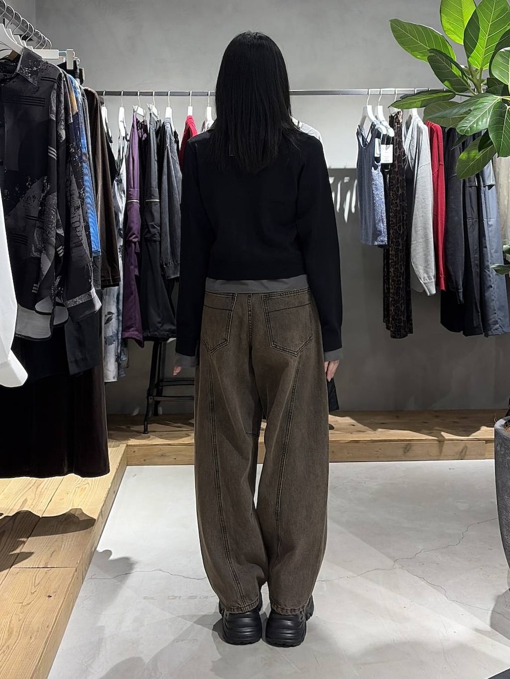 ブラウン系のデニムパンツ、ブラック系のスニーカー、ブラック系のカーディガン/ボレロを着用したレディースの秋コーディネートの3枚目の写真