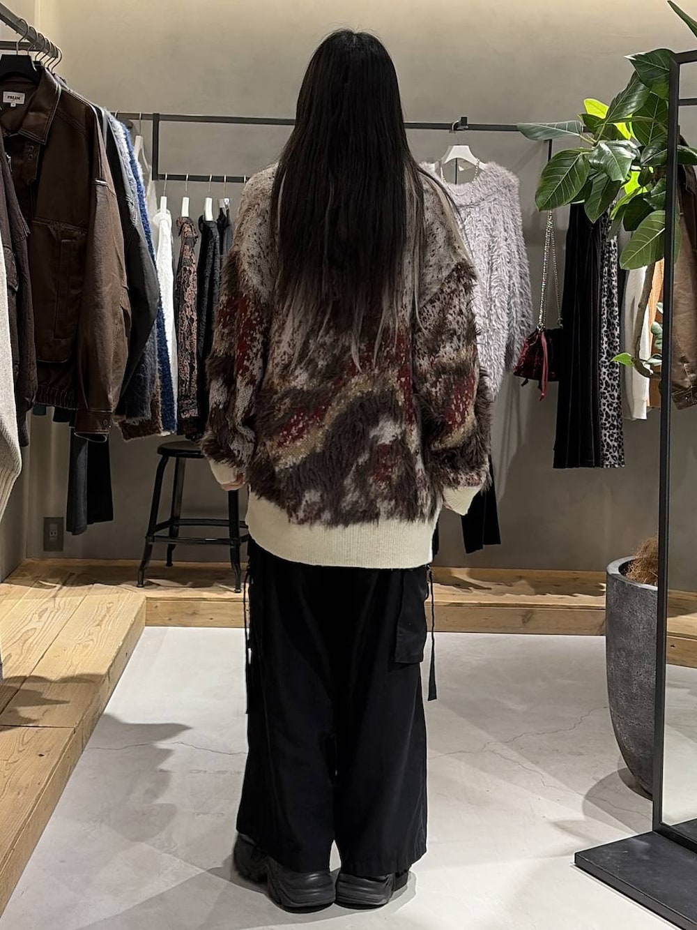 ブラック系のブーツ、ブラック系のスラックス、ホワイト系のカーディガン/ボレロを着用したレディースの冬コーディネートの3枚目の写真