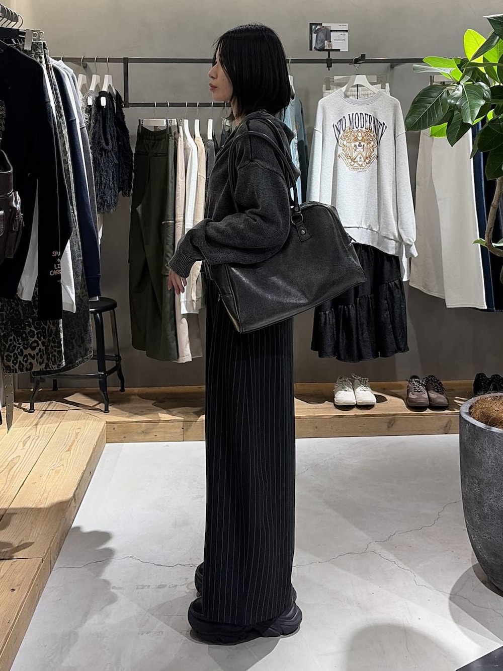 ブラック系のボストンバッグ、ブラック系のスラックス、グレー系のパーカーを着用したレディースの冬コーディネートの2枚目の写真