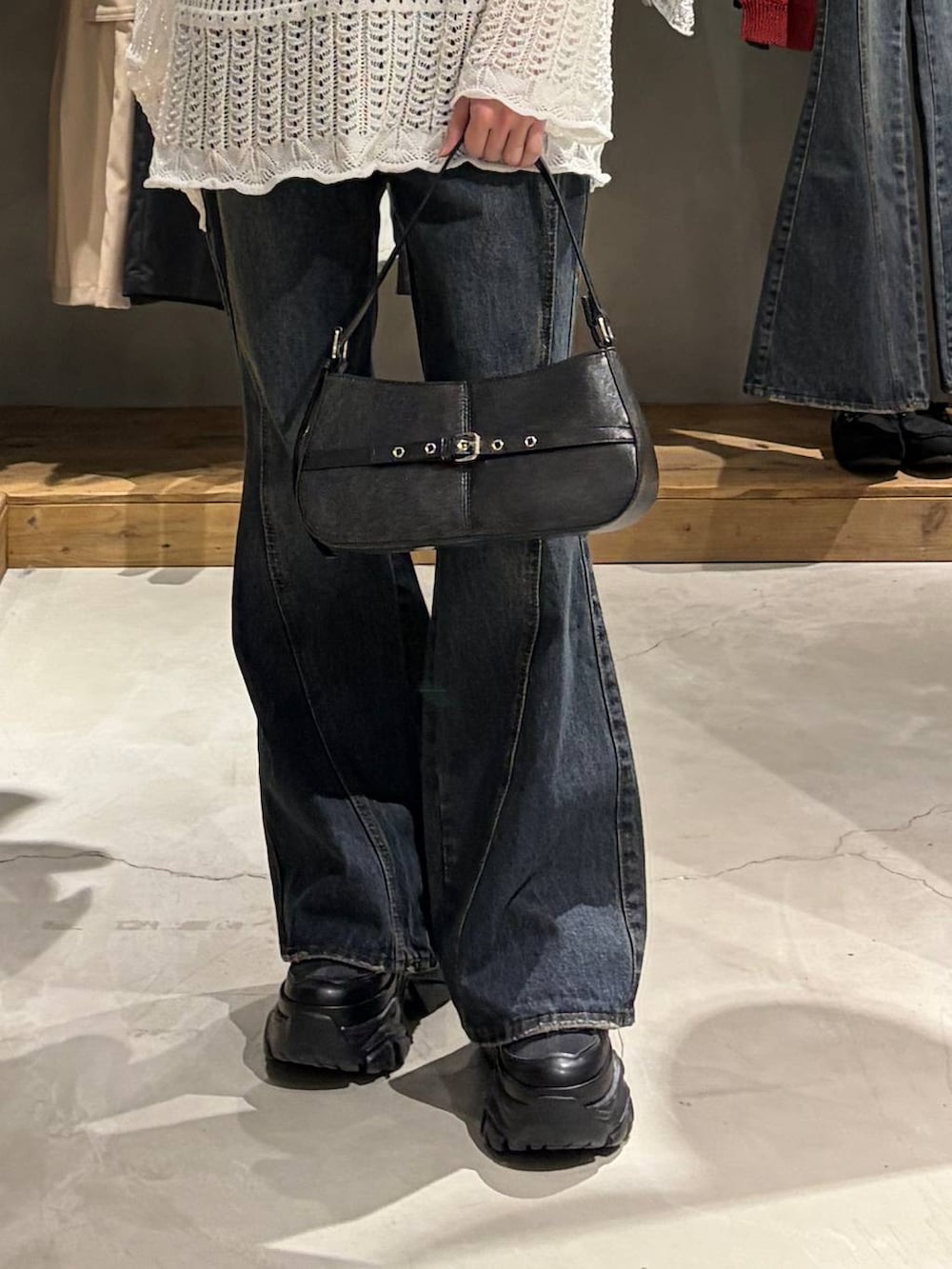 ブラック系のブーツ、ブルー系のデニムパンツ、ブラック系のハンドバッグを着用したレディースの春コーディネートの5枚目の写真