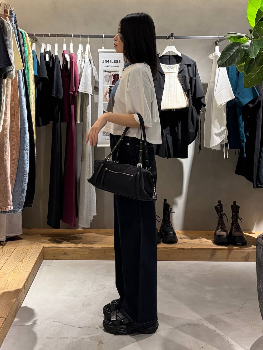ブルー系のデニムパンツ、ブラック系のサンダル、ブラック系のトートバッグを着用したレディースの春コーディネートの2枚目の写真