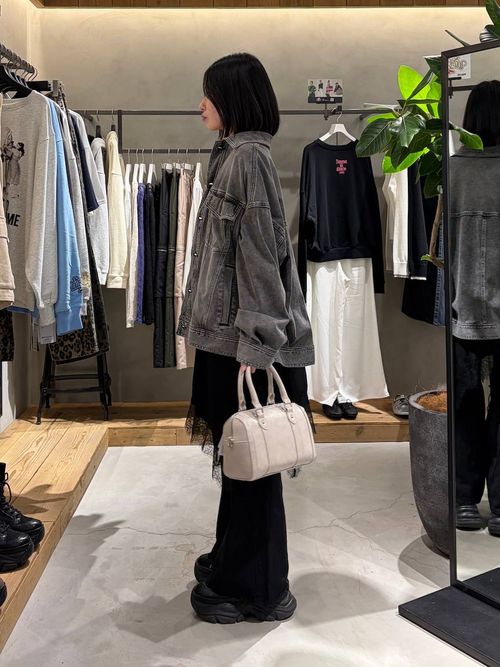 ブラック系のブーツ、ブラック系のデニムパンツ、ホワイト系のボストンバッグを着用したレディースの冬コーディネートの2枚目の写真