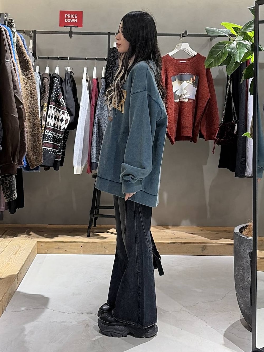 ブラック系のブーツ、ブルー系のデニムパンツ、グリーン系のスウェットを着用したレディースの冬コーディネートの2枚目の写真