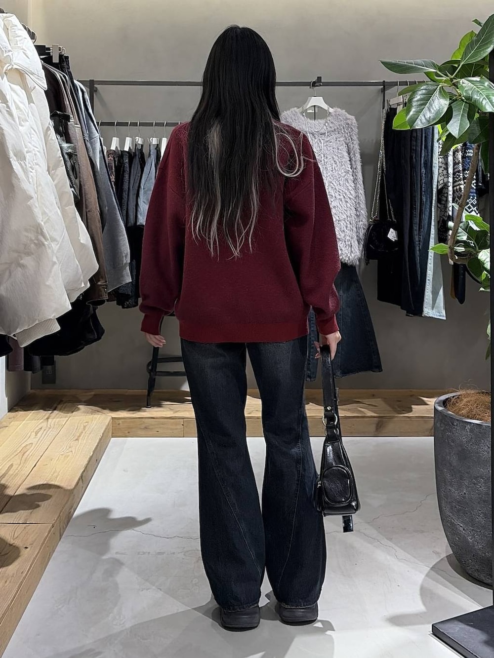 ブラック系のブーツ、ブルー系のデニムパンツ、ブラック系のショルダーバッグを着用したレディースの冬コーディネートの3枚目の写真