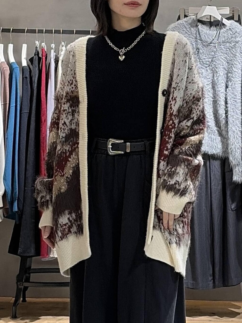 ブラック系のブーツ、ホワイト系のカーディガン/ボレロ、ブラック系のニット/セーターを着用したレディースの冬コーディネートの4枚目の写真