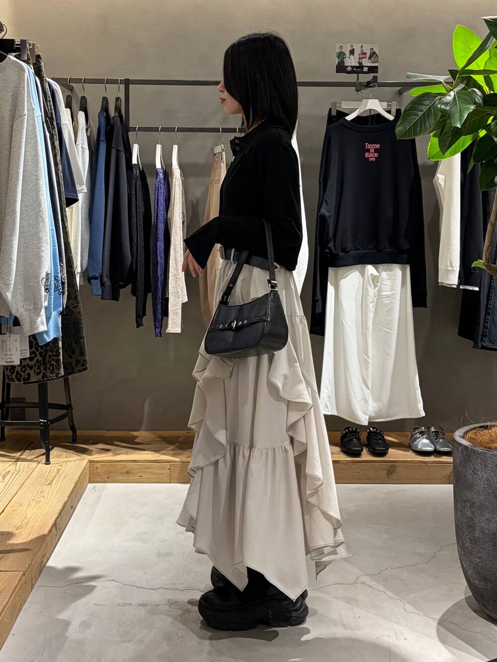 ベージュ系のスカート、ブラック系のハンドバッグ、ブラック系のカーディガン/ボレロを着用したレディースの春コーディネートの2枚目の写真