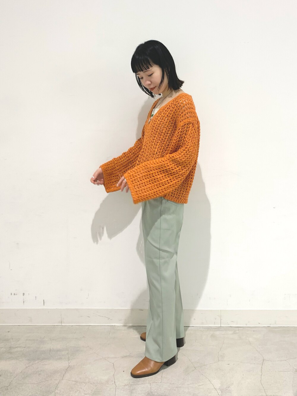 オレンジ系のニット/セーター、グレー系のTシャツ/カットソーを着用したレディースの冬コーディネートの2枚目の写真