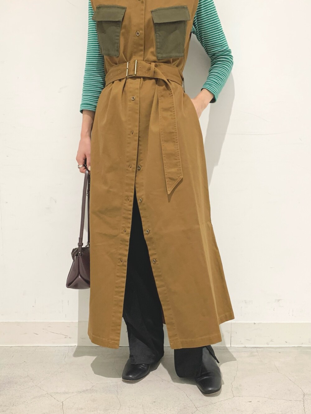 ブラウン系のベスト、ブラック系のパンツ、パープル系のショルダーバッグを着用したレディースの秋コーディネートの4枚目の写真