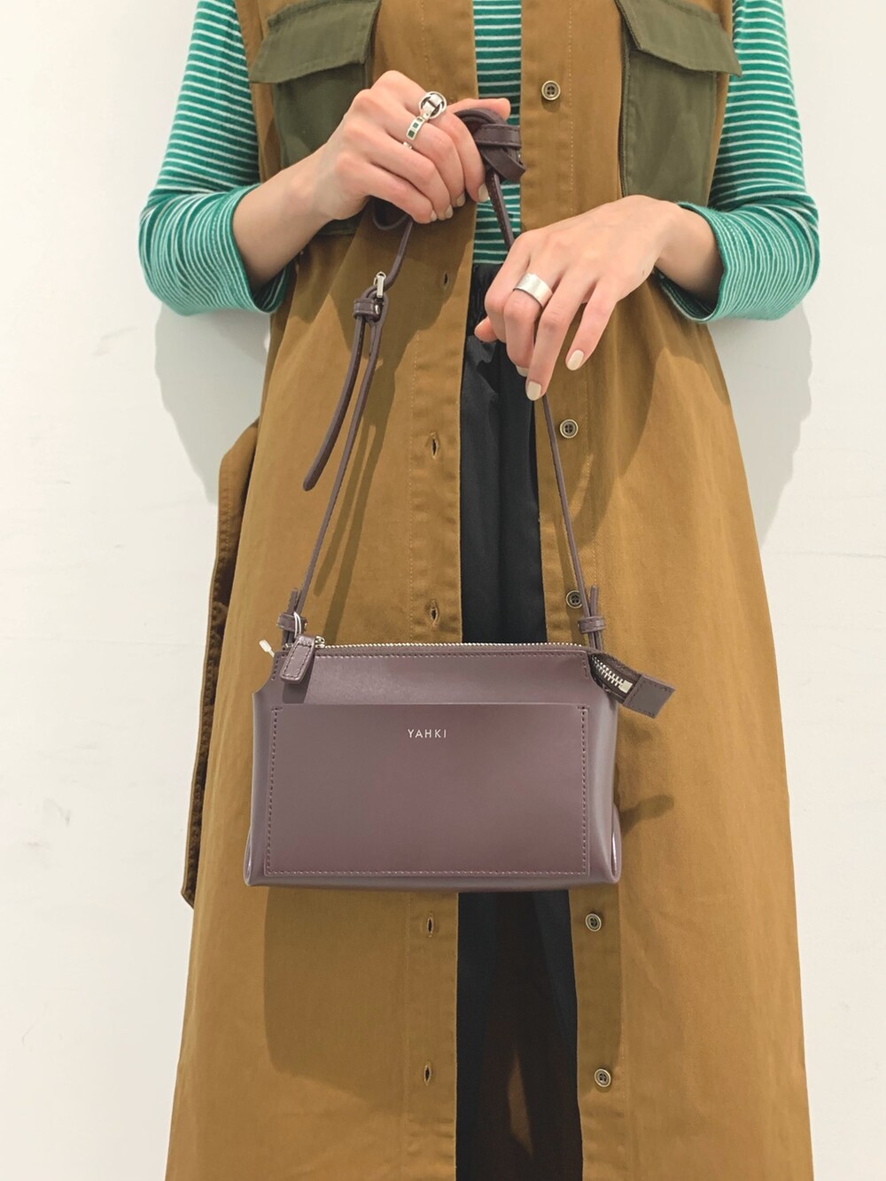 ブラウン系のベスト、ブラック系のパンツ、パープル系のショルダーバッグを着用したレディースの秋コーディネートの5枚目の写真