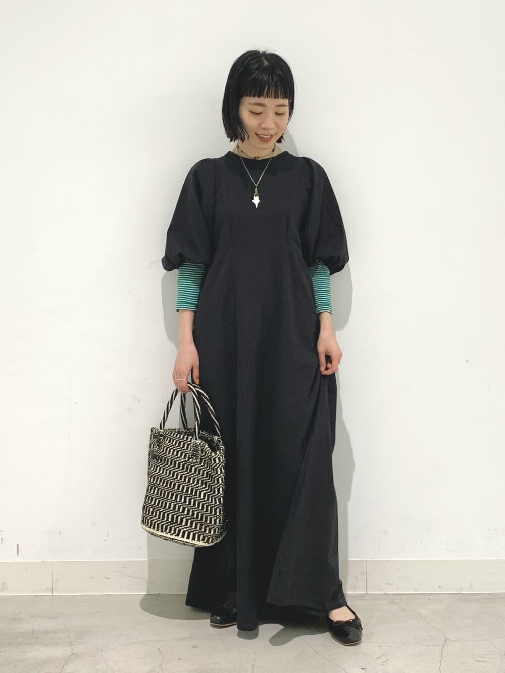 ブラック系のワンピース、ブラック系のかごバッグを着用したレディースの春コーディネートの2枚目の写真