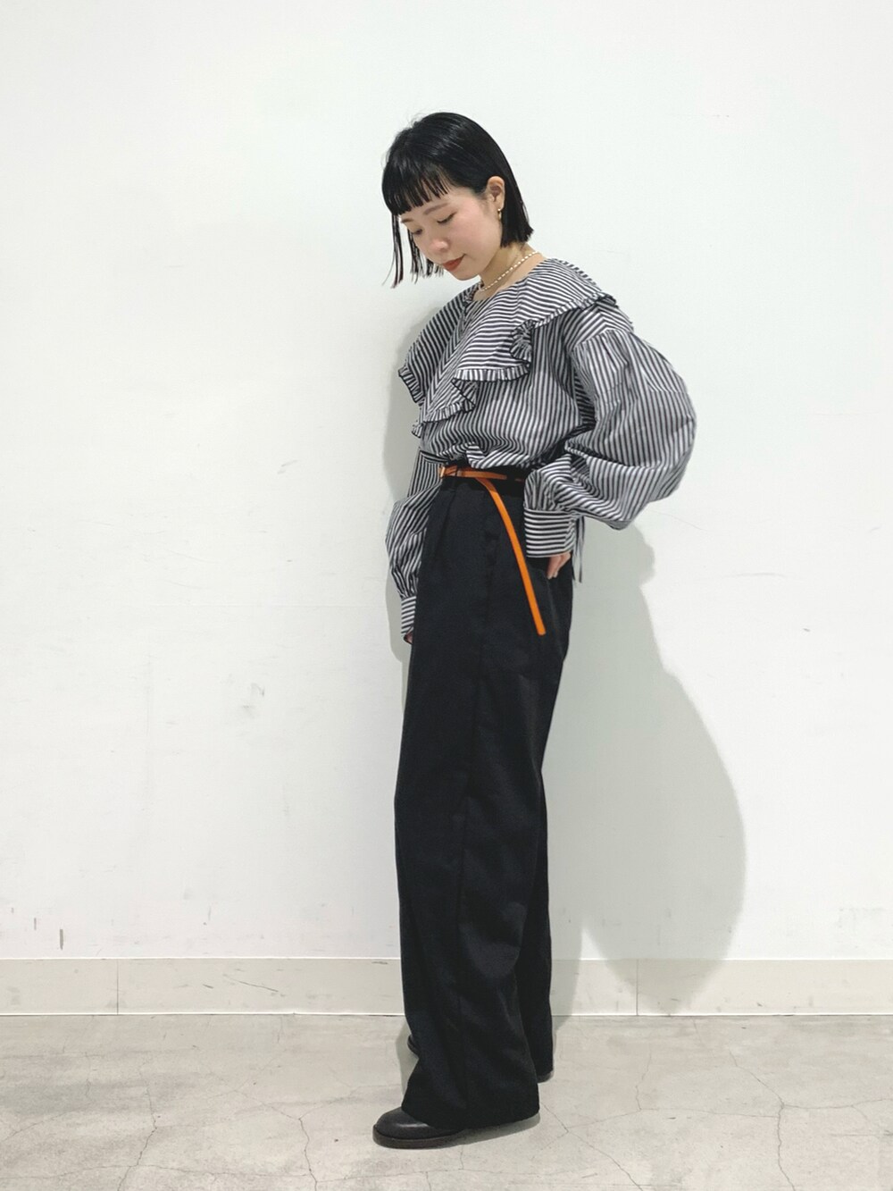 ブラック系のシャツ/ブラウス、ブラック系のチノパンツ、イエロー系のベルトを着用したレディースの春コーディネートの2枚目の写真