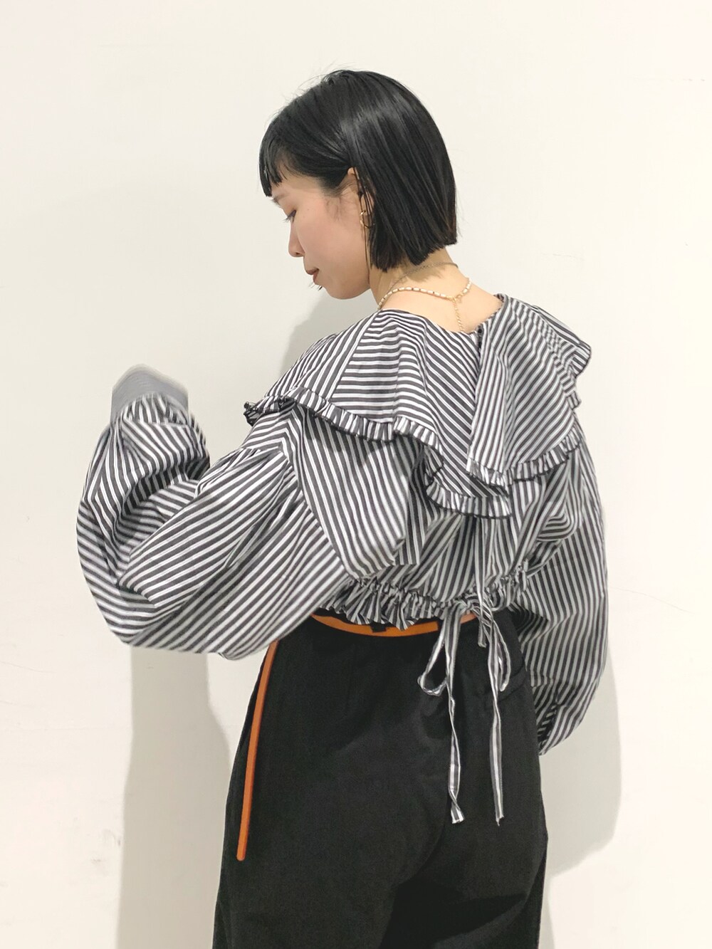 ブラック系のシャツ/ブラウス、ブラック系のチノパンツ、イエロー系のベルトを着用したレディースの春コーディネートの3枚目の写真