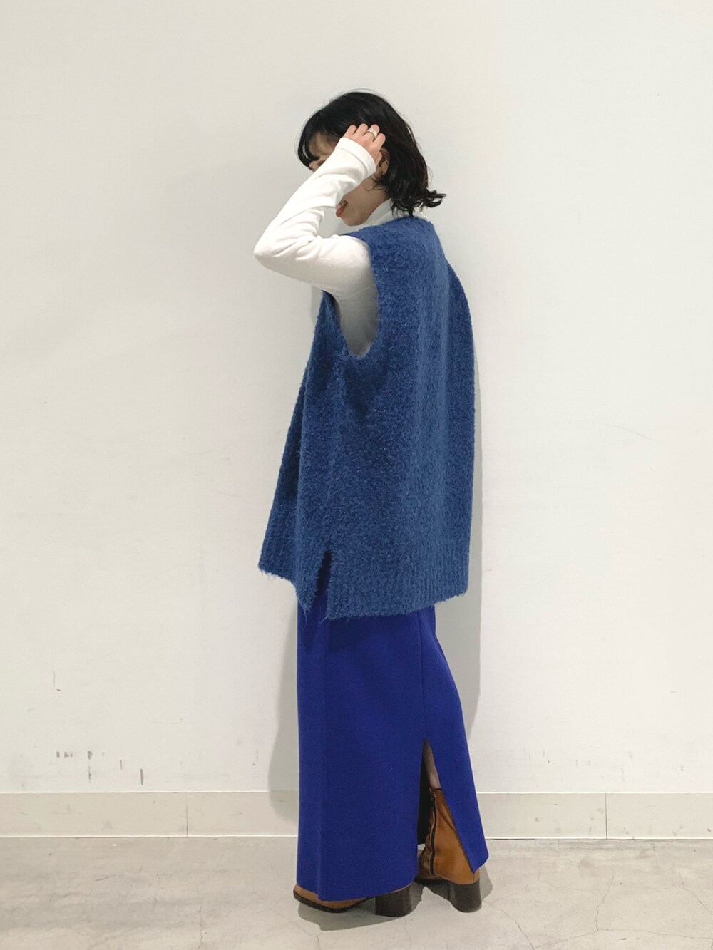 ブルー系のベスト、ブルー系のスカート、ホワイト系のTシャツ/カットソーを着用したレディースの秋コーディネートの2枚目の写真