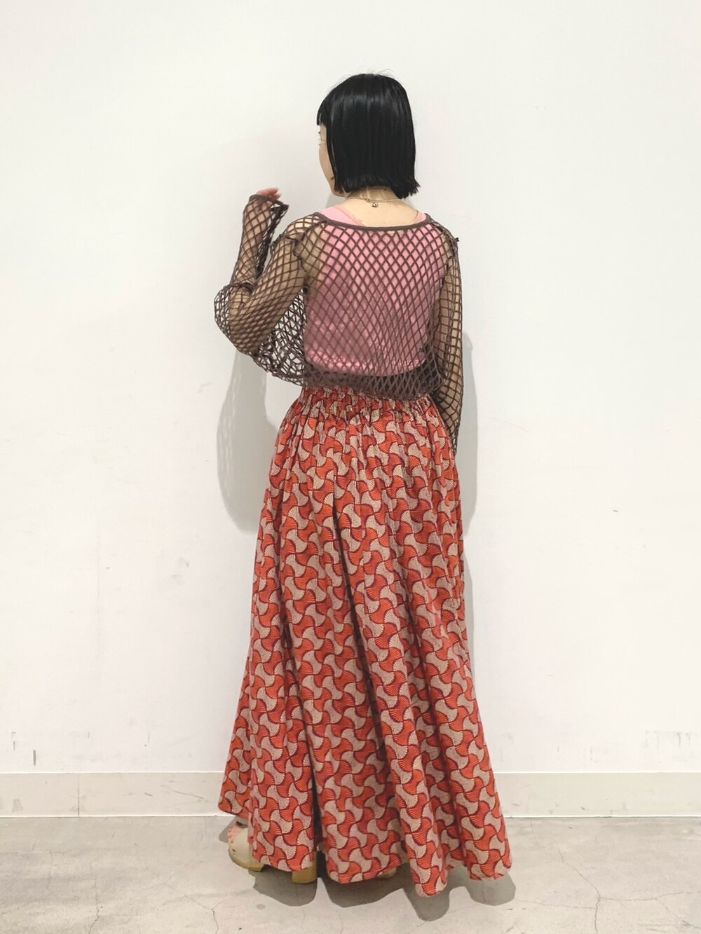 レッド系のスカート、ブラウン系のTシャツ/カットソーを着用したレディースの春コーディネートの2枚目の写真