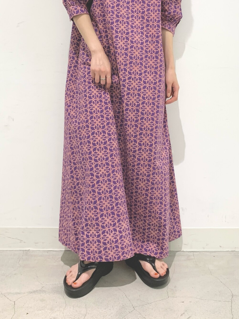 パープル系のワンピース、ブラック系のサンダル、ブラック系のハットを着用したレディースの夏コーディネートの5枚目の写真