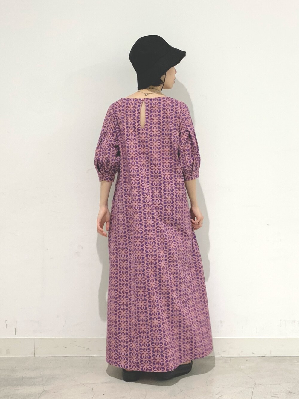 パープル系のワンピース、ブラック系のサンダル、ブラック系のハットを着用したレディースの夏コーディネートの2枚目の写真