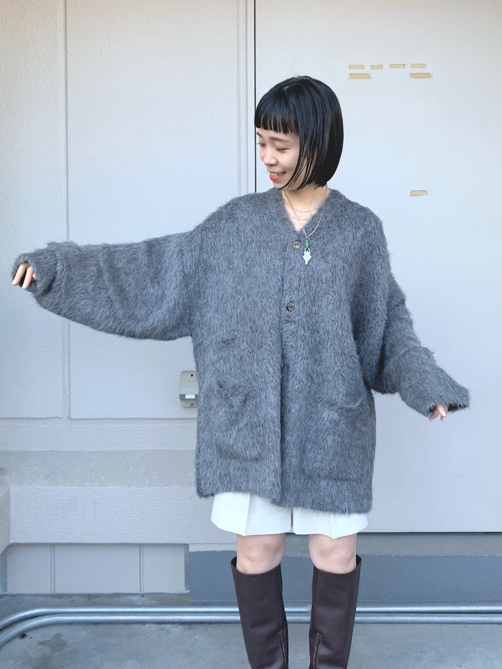 グレー系のニット/セーター、ブルー系のダウンベスト、ブラウン系のブーツを着用したレディースの秋コーディネートの4枚目の写真