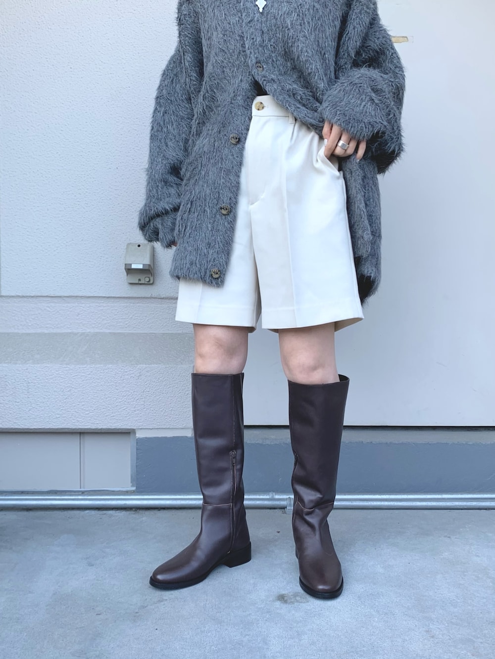 グレー系のニット/セーター、ブルー系のダウンベスト、ブラウン系のブーツを着用したレディースの秋コーディネートの5枚目の写真