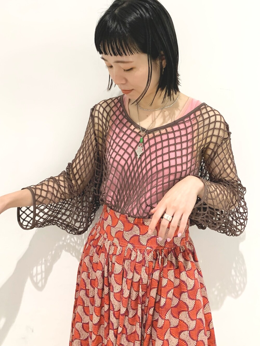 レッド系のスカート、ブラウン系のTシャツ/カットソーを着用したレディースの春コーディネートの3枚目の写真