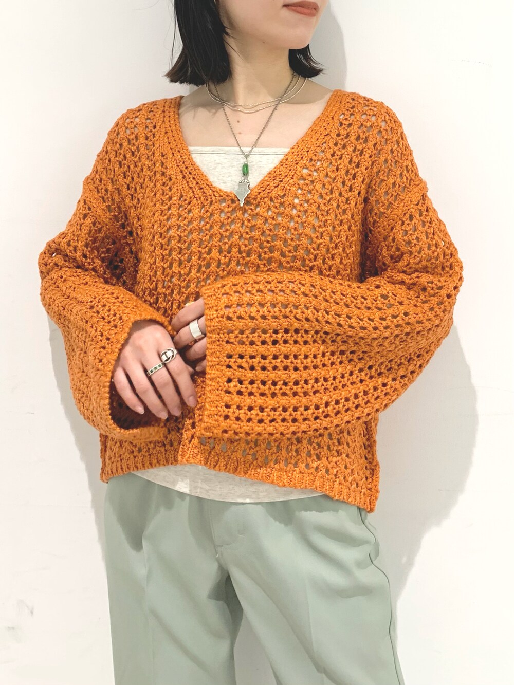 オレンジ系のニット/セーター、グレー系のTシャツ/カットソーを着用したレディースの冬コーディネートの3枚目の写真